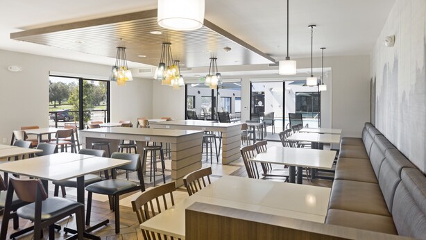 Un restaurante moderno con mesas altas, cabinas y una isla central.