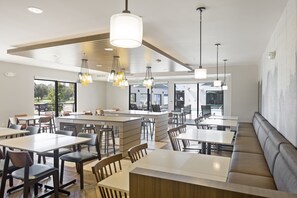 Un restaurante moderno con mesas altas, cabinas y una isla central.