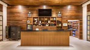 A reception area with a wooden reception desk, shelves with various items, and a television mounted on the wall. - Four Points by Sheraton Monterrey Airport (Apodaca)