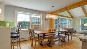 A spacious dining area with a wooden table and chairs, large windows, and a view of greenery outside. - Chic Dover Home w/ Hot Tub: 1 Mi to Golf! (West Dover)