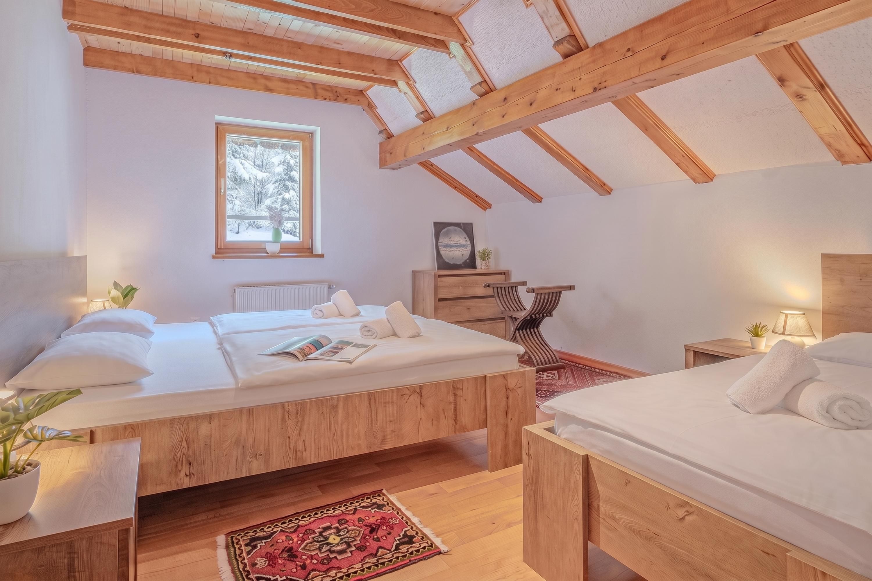 Un dormitorio con techo de madera, ventana con vistas, cama, mesita de noche y alfombra.