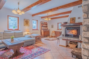 Un salon chaleureux avec une cheminée, des poutres apparentes, un canapé, une table basse et un tapis.
