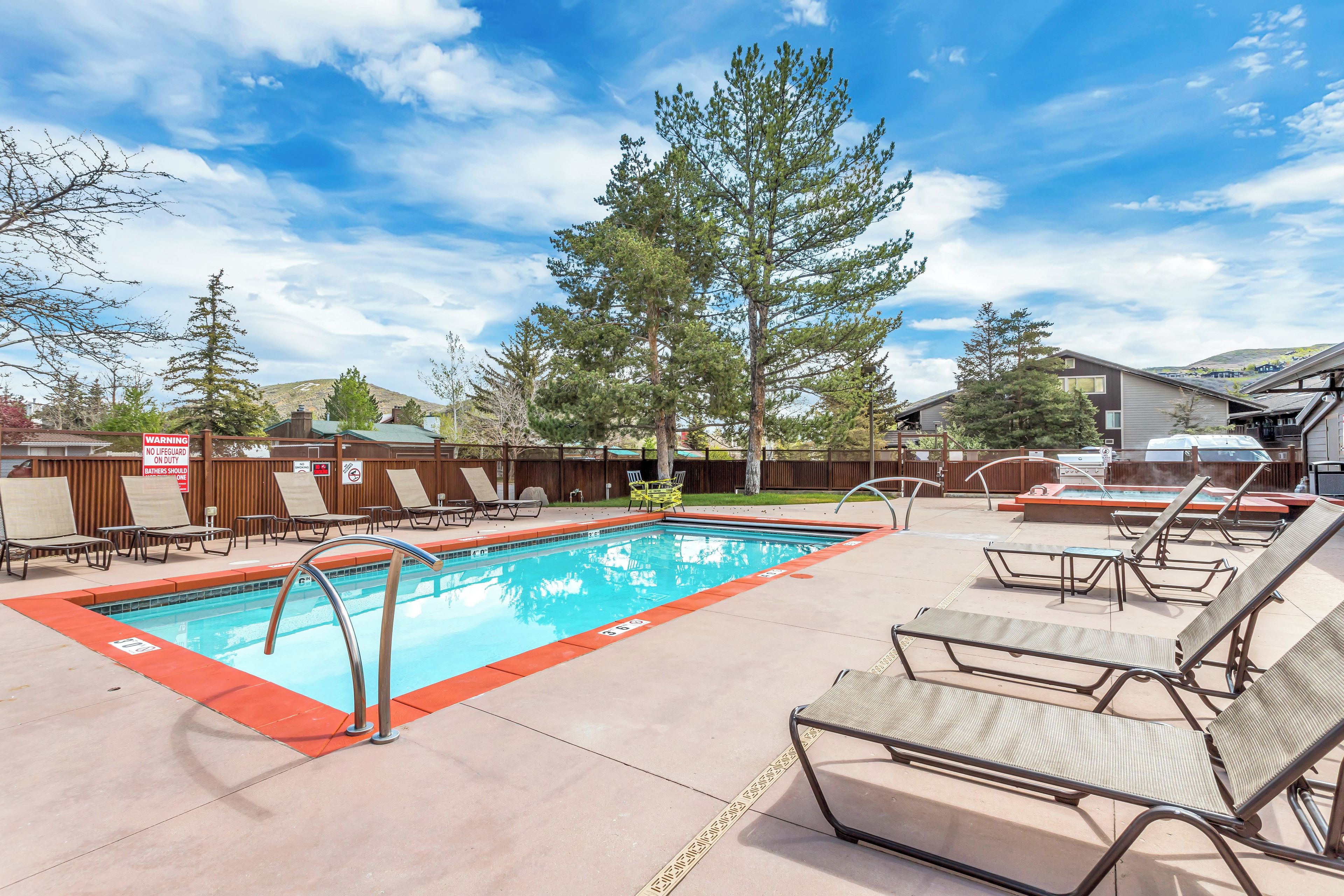 A swimming pool with lounge chairs and a wooden fence.
