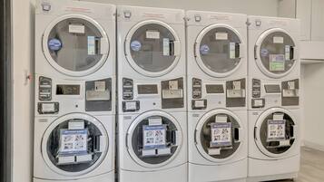 A row of four stacked laundry machines with control panels and detergent dispensers.