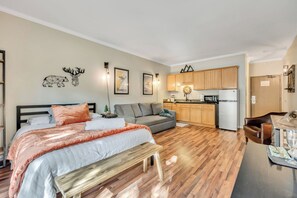 Eine moderne Wohnung mit Bett, Sofa, Esstisch, Küche und einer kleinen Sitzecke.
