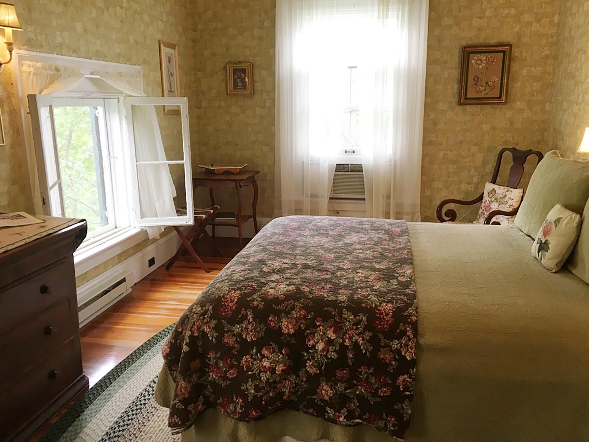 A bedroom with a bed, dresser, and window with curtains.