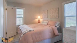 Een slaapkamer met een bed, een bedlamp en twee decoratieve wandobjecten.