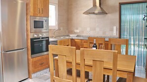 Une cuisine moderne dotée d’appareils électroménagers en acier inoxydable, de meubles en bois et d’un coin repas avec une table et des chaises.