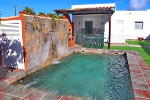 Una piscina con un muro de piedra y una pequeña cascada.