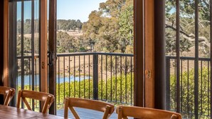 A wooden deck with a table and chairs, overlooking a natural landscape with trees and a body of water. - Rustic charm amongst the vines in Pokolbin (Pokolbin)