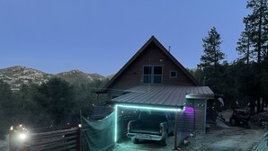 En hytte med carport, grusvej og bjergudsigt.