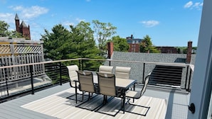 Eine Dachterrasse mit Tisch und Stühlen und Blick auf ein historisches Geb äude, sowie ein Holzterrasse.