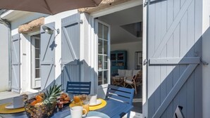 A breakfast table set with fruits, juice, and coffee, with a view of a blue chair and a wicker basket. - Bretagne by Interhome (Carnac)