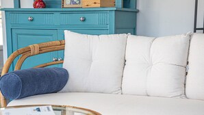 A wicker sofa with white cushions and a rolled-up blue blanket. - Bretagne by Interhome (Carnac)