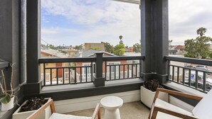 Ein Balkon mit Blick auf die Stadtlandschaft, ein weißer Tisch und Kübelpflanzen.