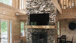 Ein Holzblockhaus-Interieur mit Kamin aus Stein, Holzwänden und einem Essbereich.