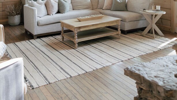 Ein Holzblock-Innenraum mit einer Couch, einem Couchtisch und großen Fenstern.