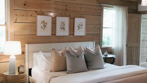 Ein Schlafzimmer mit Holzwänden, einem großen Bett, Nachttischen und gerahmten Kunstwerken an der Wand.