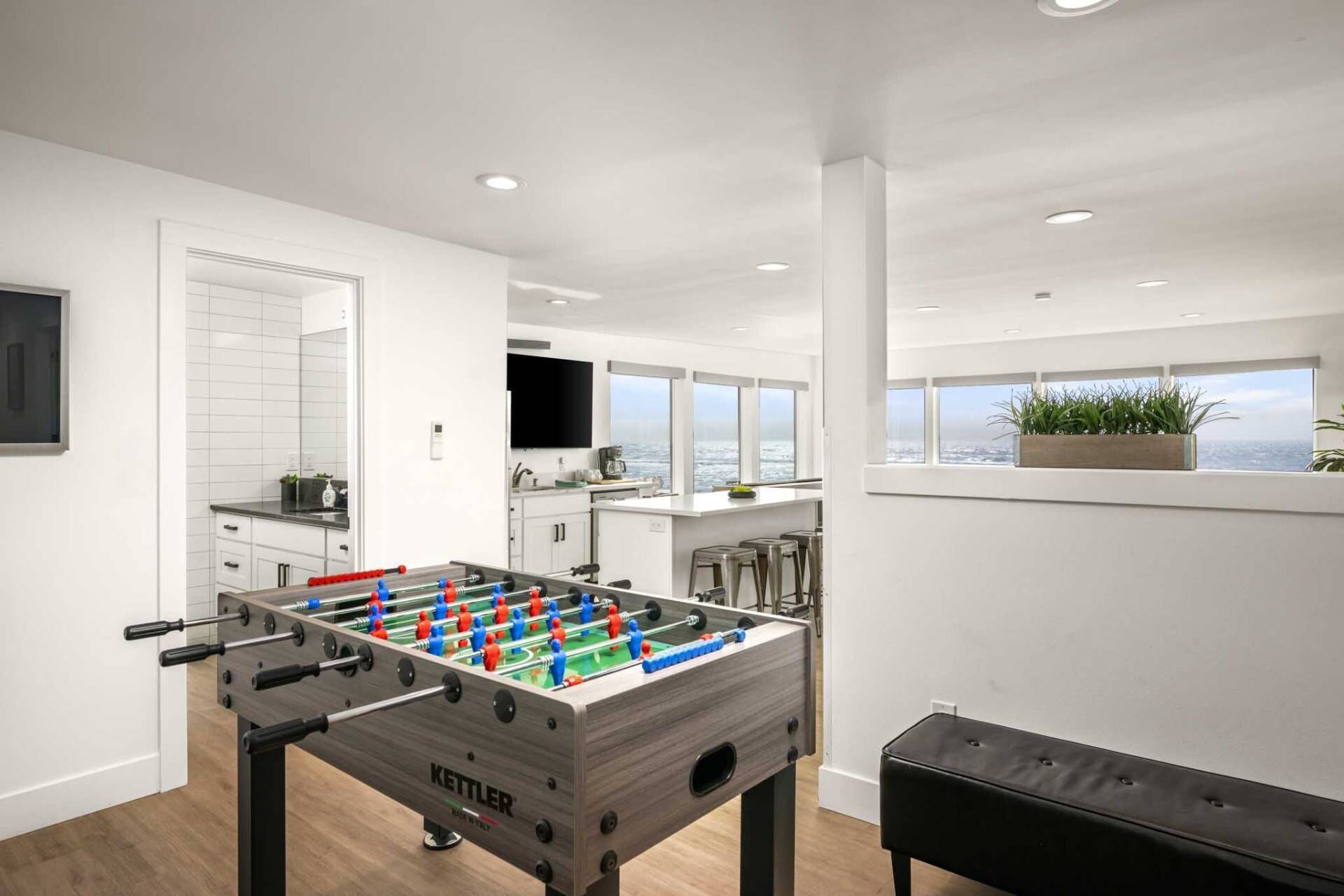 Una cucina moderna con tavolo da calcio, angolo bar e una grande finestra con vista sull'oceano.