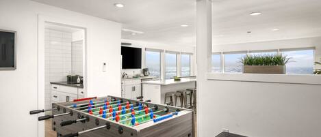 Una cucina moderna con tavolo da calcio, angolo bar e una grande finestra con vista sull'oceano.