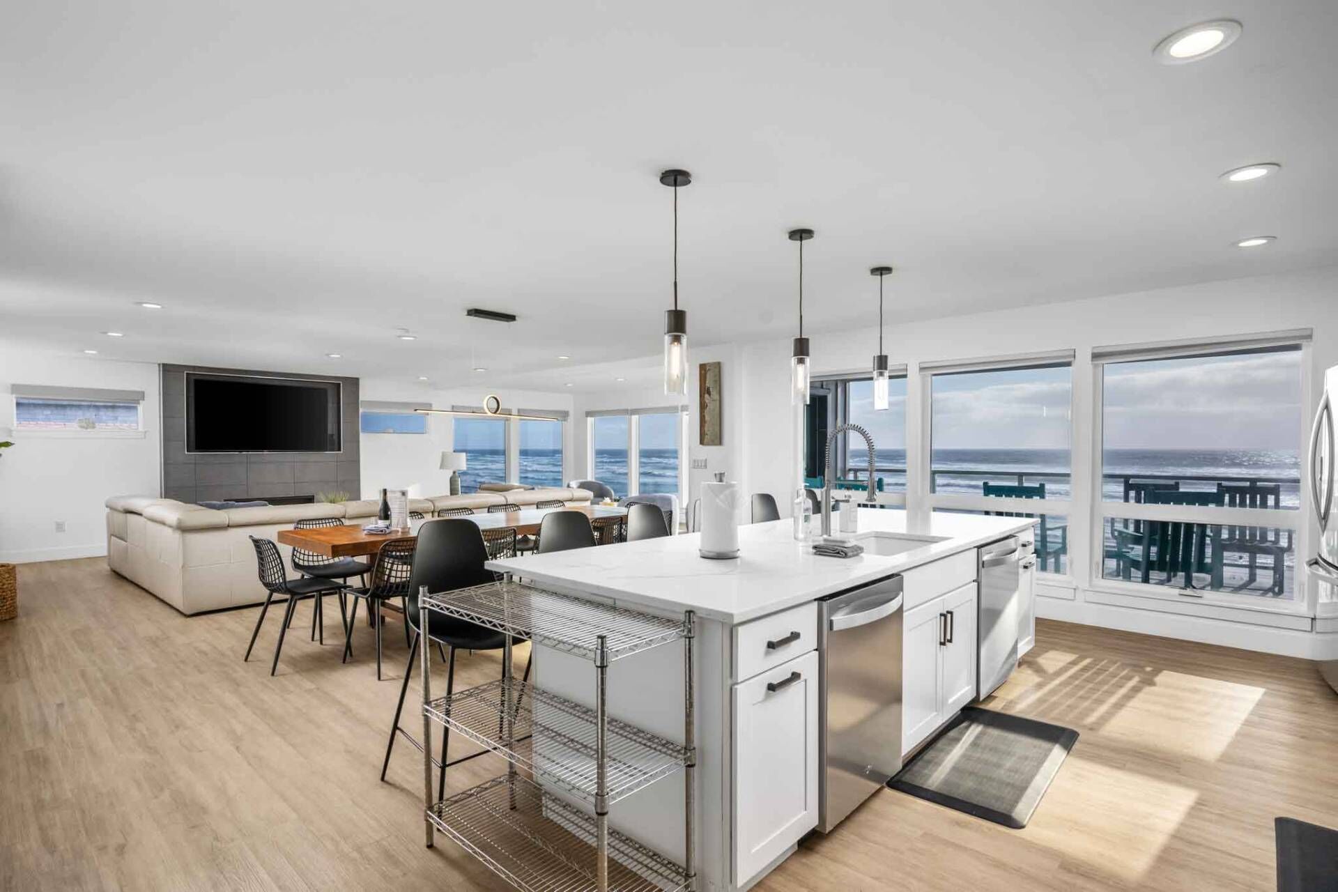 Une cuisine moderne dotée d’un grand îlot central, d’un coin repas offrant une vue agréable et d’un espace de vie avec un grand téléviseur et des sièges confortables.