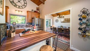 A modern kitchen with a wooden island, stainless steel appliances, and a large wall clock. - Phenomenal Mid-Century Modern Retreat, Open Layout, Fenced Backyard, Fire-Pit, 10 Miles to Portland (Beaverton)