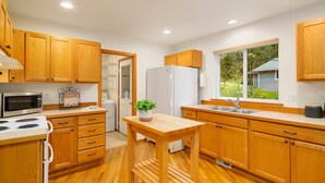 Eine moderne Küche mit Holzschränken, einem weißen Kühlschrank, einer Mikrowelle und einem Spülbecken.