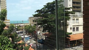 Une vue depuis une fenêtre donnant sur une rue, avec des immeubles, un camion garé et un arbre.