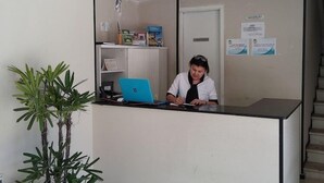 Un comptoir d’accueil avec un ordinateur portable, une plante en pot et un escalier en arrière-plan.