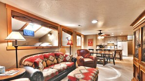 Ein gemütliches Wohnzimmer mit Sofa, Sessel, Hocker und einem Essbereich mit Tisch und Stühlen.