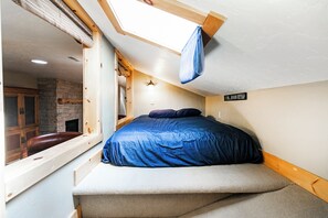 A bedroom with a bed, a window, a stone fireplace, and a sign indicating a rooming house. - Top Floor Prospector Condo - 3BD/3BA - Sleep up to 10 (Park City)