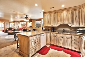 Una cocina amplia con armarios de madera, encimera de granito y ventilador de techo.