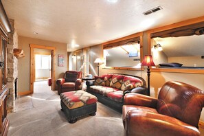 Una sala de estar acogedora con chimenea, muebles de cuero y un espejo grande.