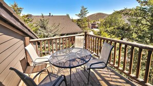 Eine Holzterrasse mit einem runden Tisch und Stühlen, umgeben von einer Holzbrüstung.