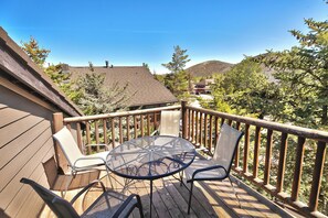Une terrasse en bois avec une table ronde et des chaises, entourée d’une balustrade en bois.