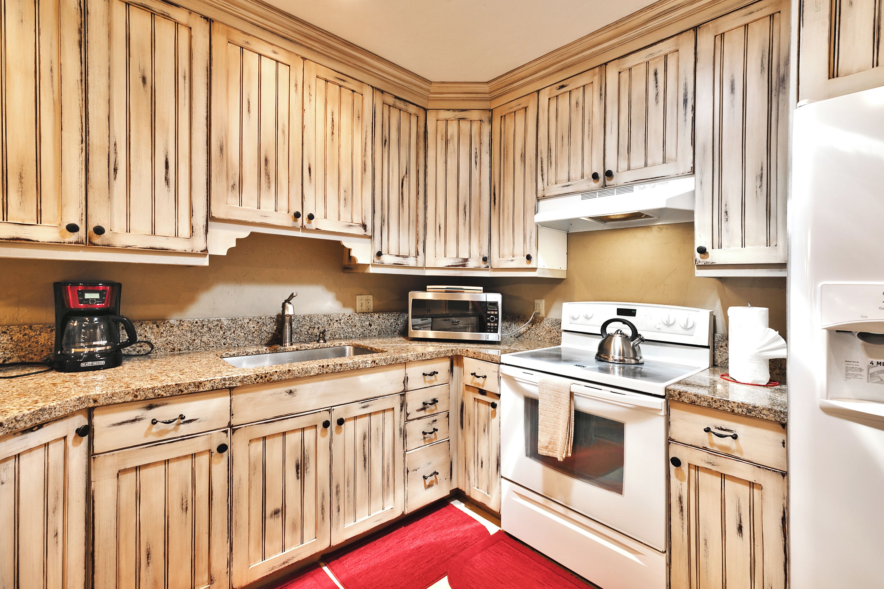 Una cocina con armarios de madera, estufa, microondas y cafetera.