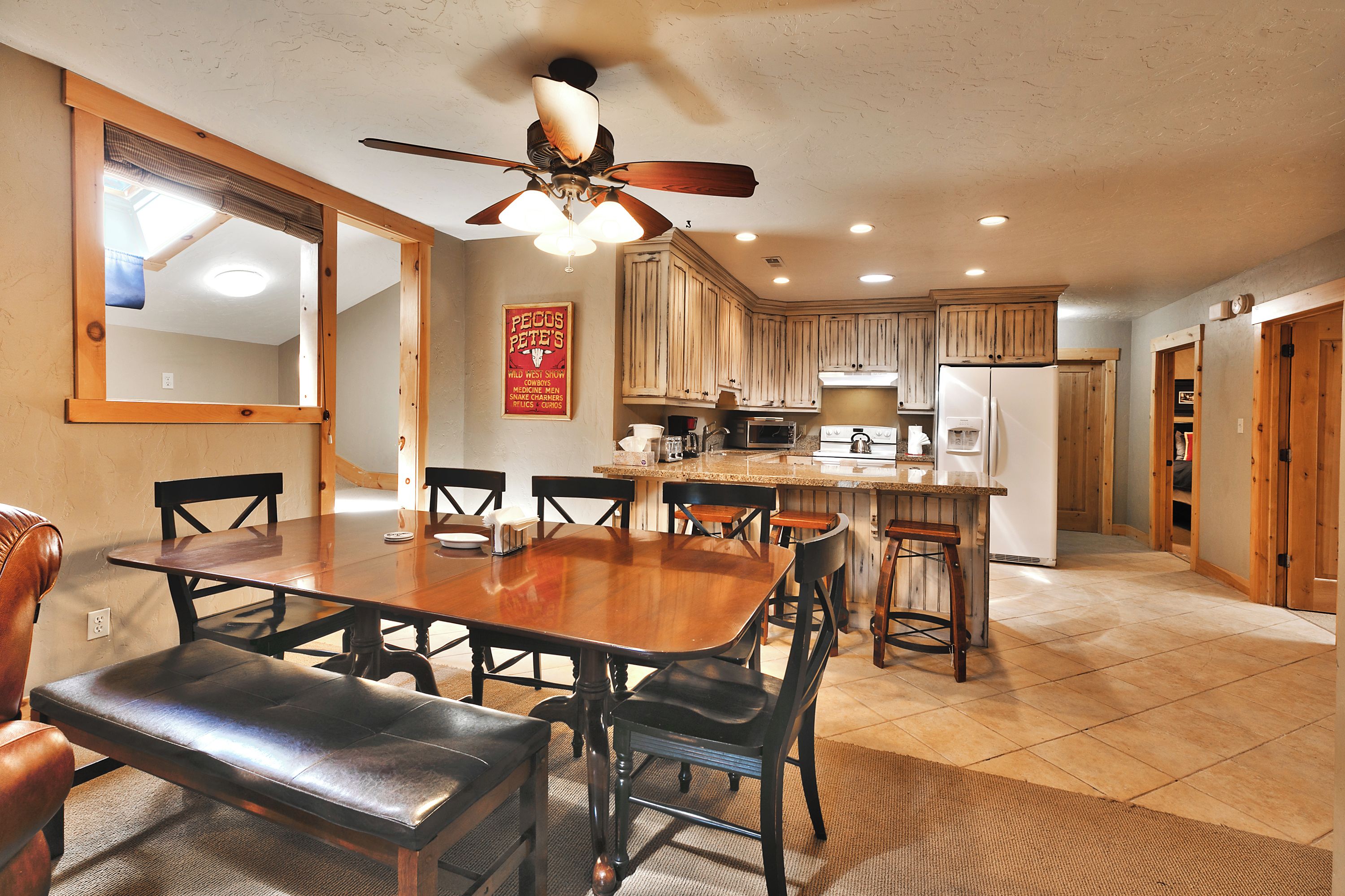 A spacious kitchen with wooden cabinets, a central island, and a dining area with a large table and chairs.