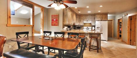 A spacious kitchen with wooden cabinets, a central island, and a dining area with a large table and chairs.