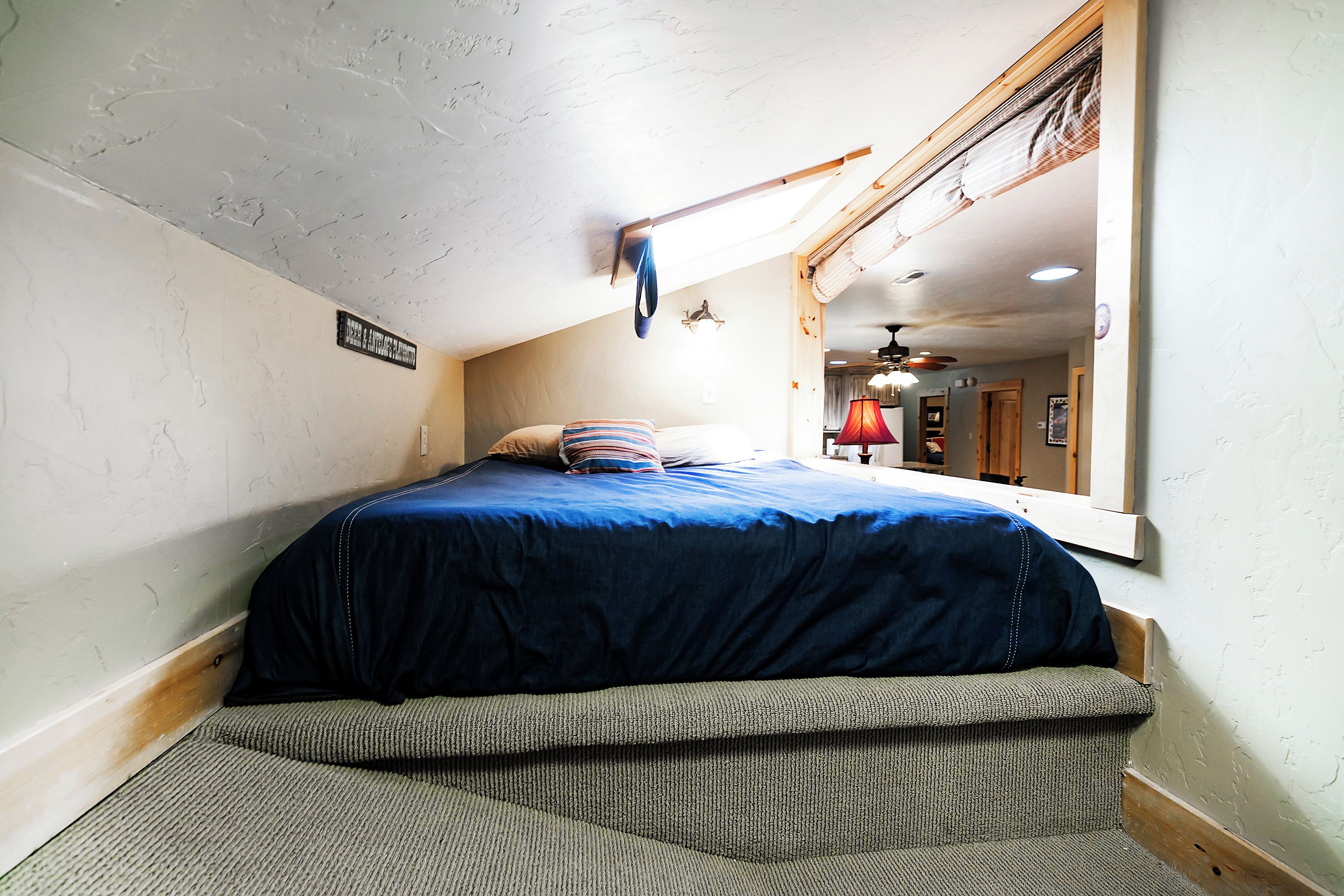 A bedroom with a bed, a hanging light fixture, and a window.