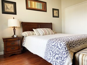 Cozy bedroom with a comfortable bed, nightstand, and artwork.
