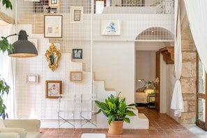 A spacious room with a high ceiling, a staircase, and a potted plant.