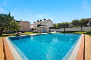 A rectangular swimming pool with a tiled edge, surrounded by a brick deck.