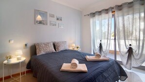 A bedroom with a bed, bedside tables, a lamp, and curtains. - Apartamento Água Brisa with Pool, Wi-Fi, A/C, Balcony & Garden (Albufeira)