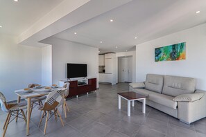 Un salon moderne comprenant un canapé, un téléviseur, une table à manger et des chaises.