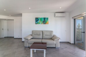 A modern living room with a sofa, a table, and a colorful abstract painting on the wall.
