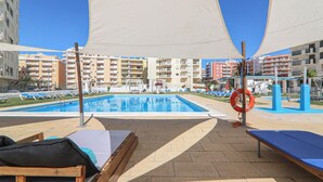 Ein Poolbereich mit Liegestühlen, einem Rettungsring und blauem Himmel.