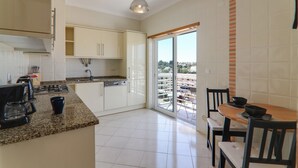 A modern kitchen with a large island, built-in appliances, and a dining area with a view. - Quinta dos Arcos Lote 18 3ºG Apartment with Sea View, Pool and Balcony (Armação de Pêra)