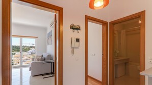 A modern apartment with a living area, a bathroom, and a view of the cityscape. - Quinta dos Arcos Lote 18 3ºG Apartment with Sea View, Pool and Balcony (Armação de Pêra)