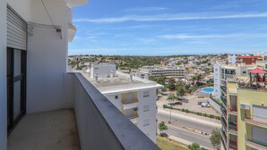 A balcony with a view of a cityscape, including buildings and a road. - Torre Sol 909 Beach Apartment with Pool, Garden, and Balcony (Armação de Pêra)