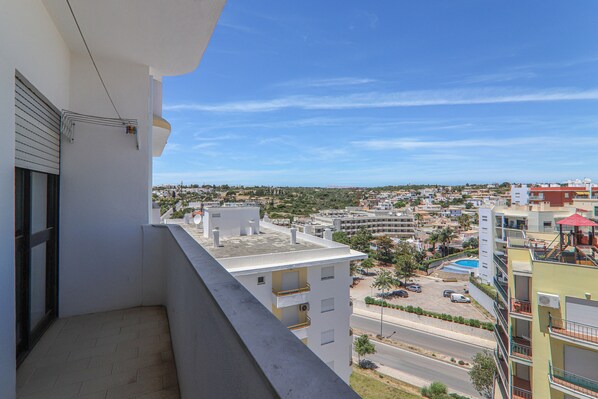 A balcony with a view of a cityscape, including buildings and a road. - Torre Sol 909 Beach Apartment with Pool, Garden, and Balcony (Armação de Pêra)